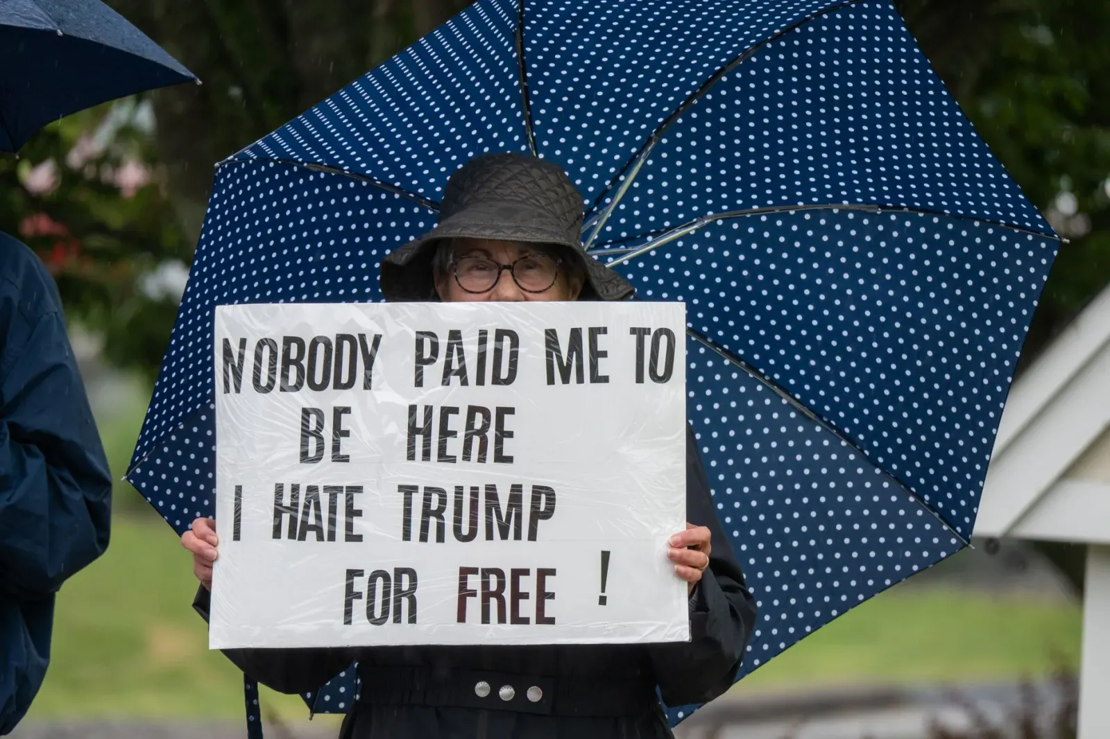 Imajen ida hatudu sinál protestu kona-ba traballu forsadu no tarifa Trump iha ruas, ho ema sira hamriuk ho kartaz