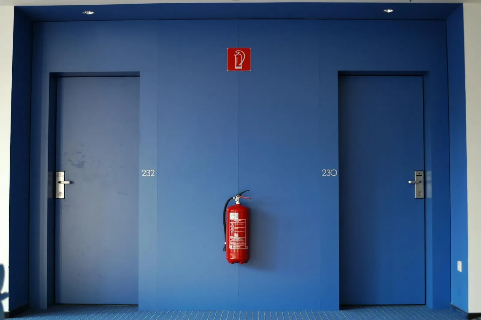 Imajen ida hatudu detector fumo iha kuartu hotel, ho luz vermelhu no tetu branku, hanesan ezemplu ba seguransa fogo iha ospit
