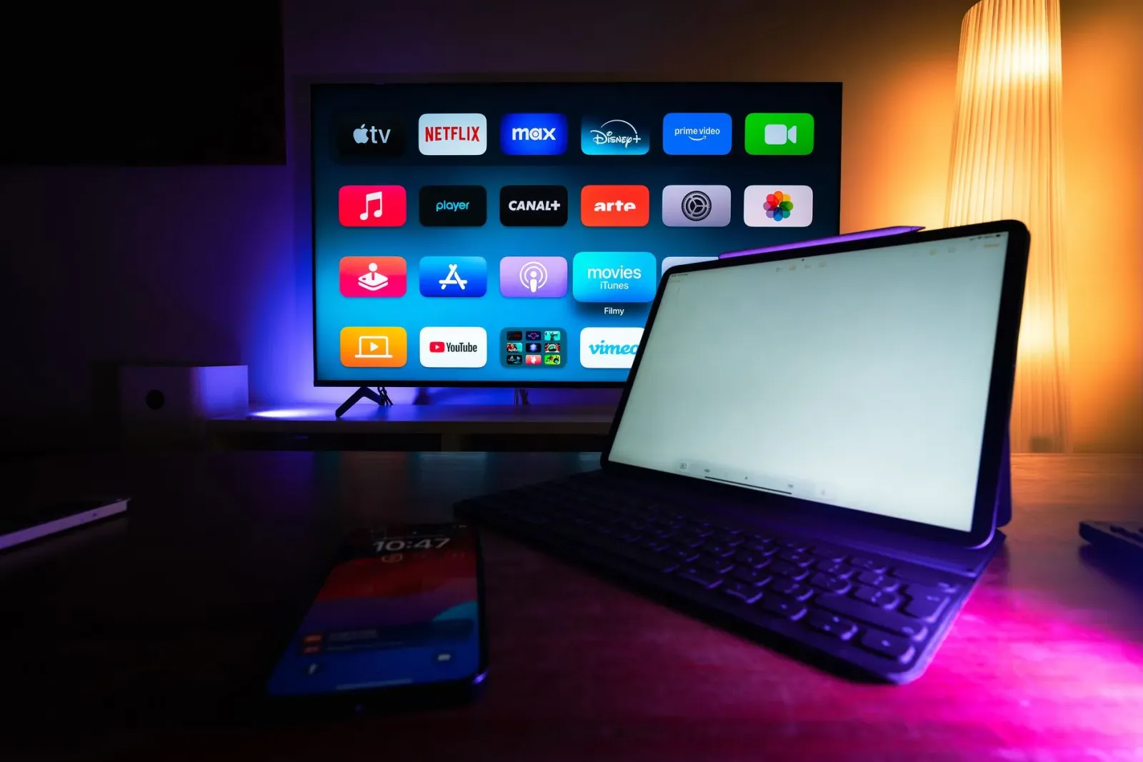 Imajen hatudu Roku streaming device hamutuk ho remote, monitor Samsung Movingstyle iha roda, no adaptador Twelve South AirFly