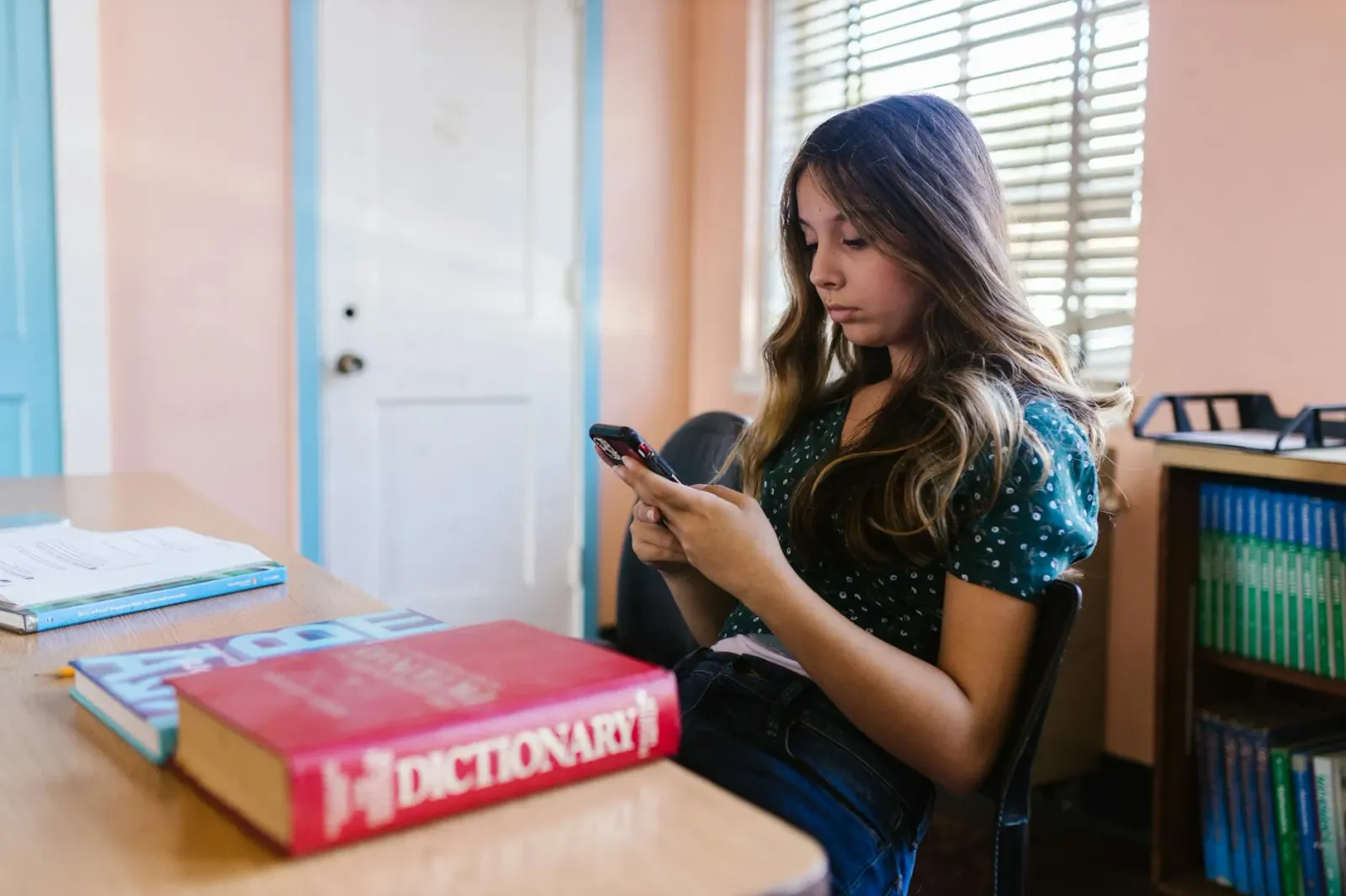 Imajen ida hatudu smartphone ho mensajen WhatsApp ne'ebé lakon depois lee, hamutuk ho estudante veterinária nia livru no tele