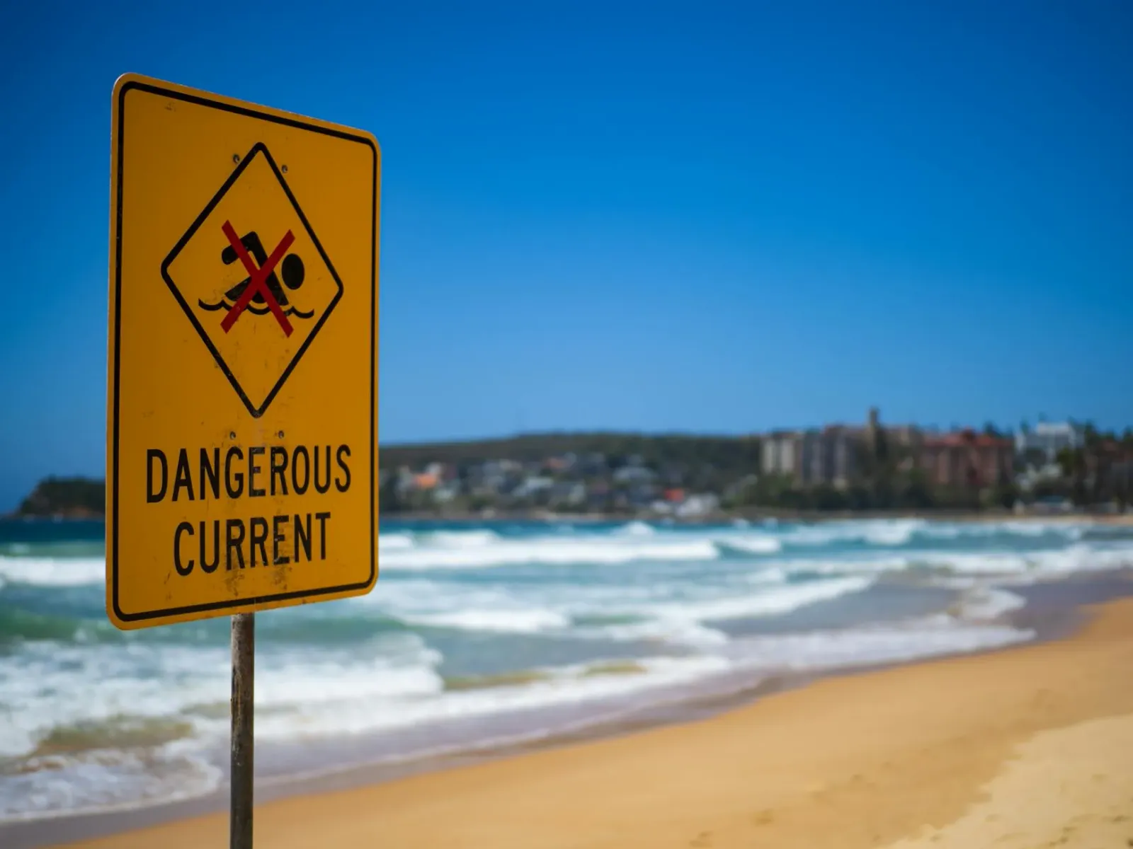Sinal avizu kona-ba atake tubaraun iha praia Australia, ho letra boot no kor mean, iha tasi nia oin