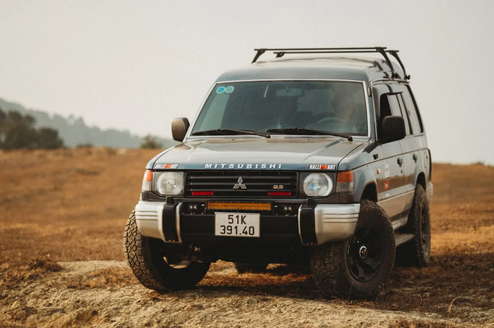 Imajen konseituál: logu Visa no Google iha fundu teknolojia, karreta Mitsubishi Pajero iha estrada off-road, no pitxer baseba