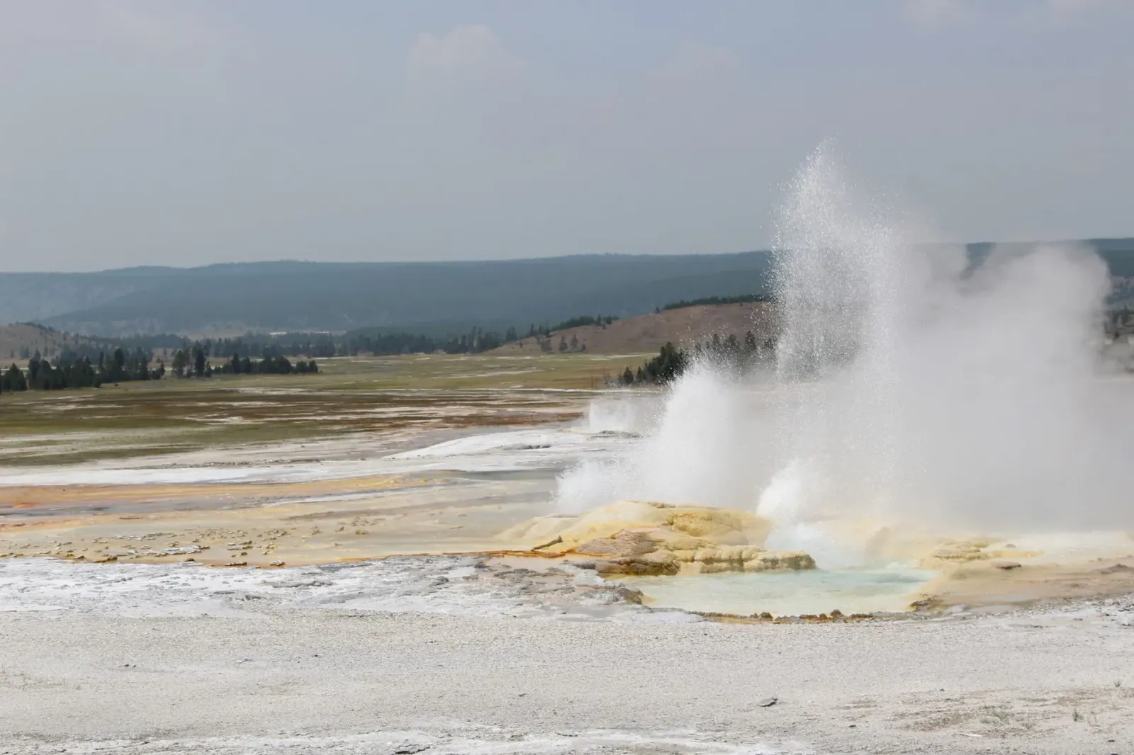 Paisajen Parque Nasional Yellowstone ho krater vulkániku boot no fumaça husi atividade termál, ilustra forsa naturál ne'ebé i