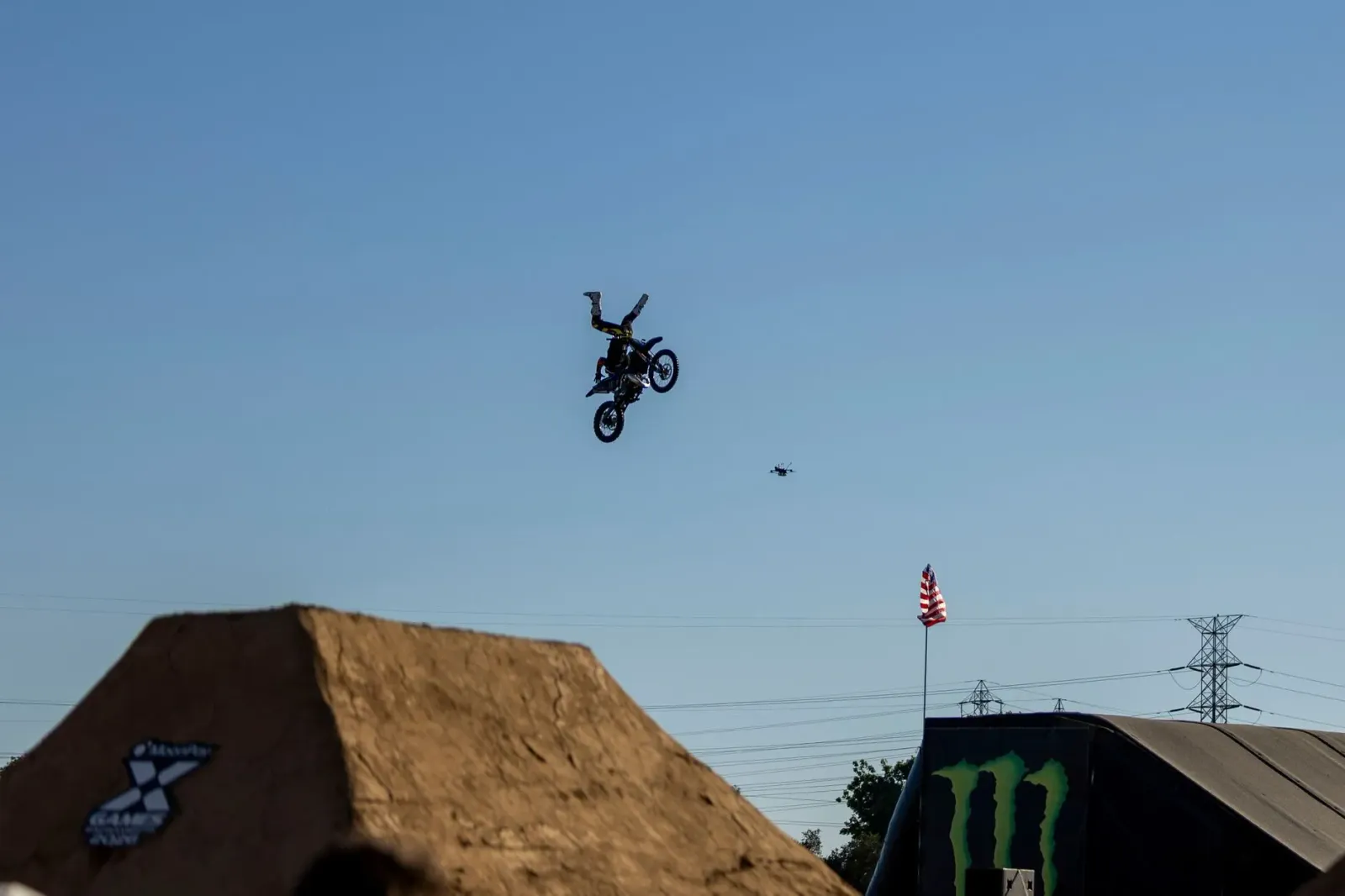 Atleta X Games salta ho motokrós iha lalehan, ho background neon no ema barak haree. Fotinhu ne'e hatudu oinsá atleta sira de