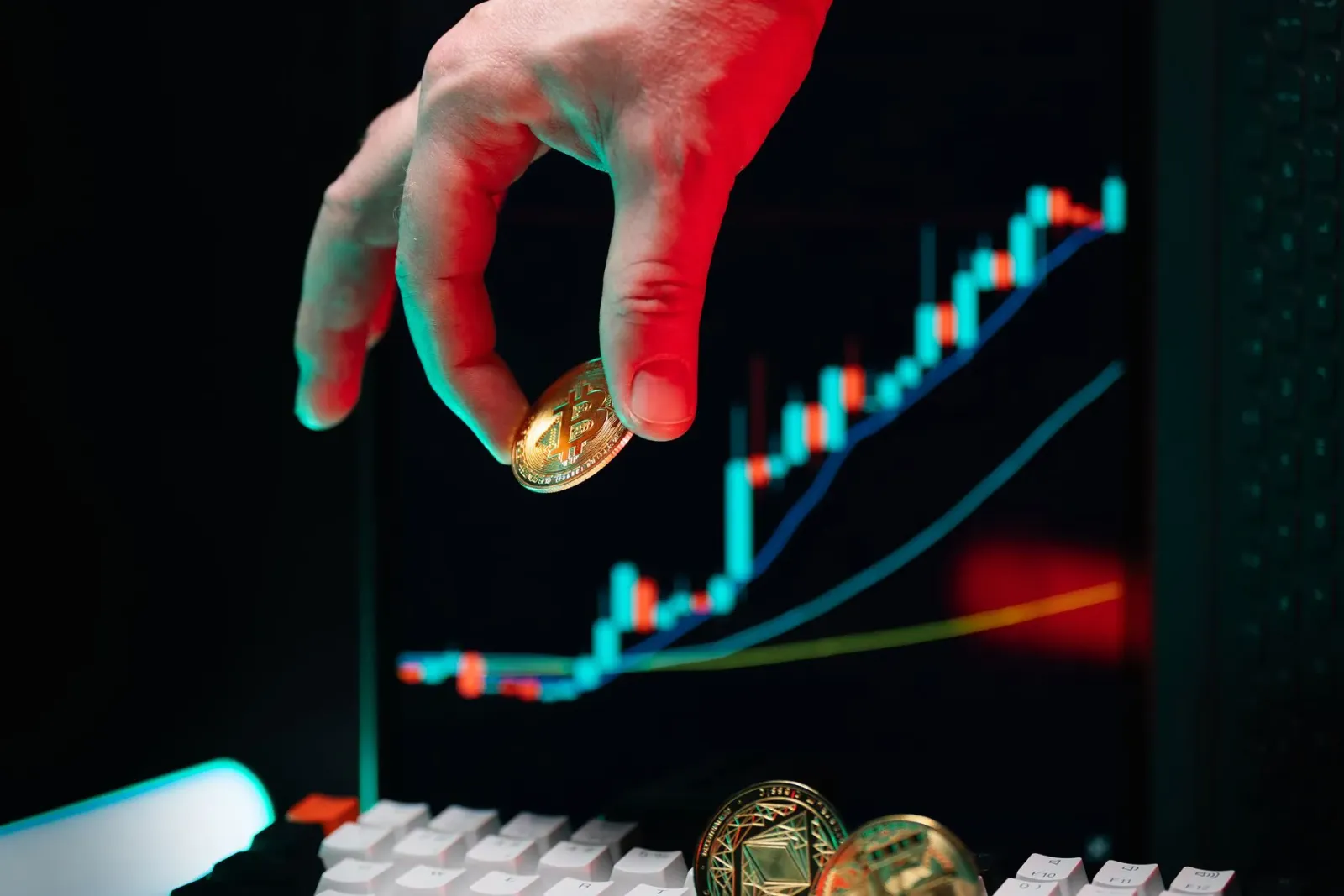 Empresáriu ida tuur iha meja ho komputadór, haree ba dokumentu no gráfiku finansas, ho símbolu kripto no seguransa síber iha 