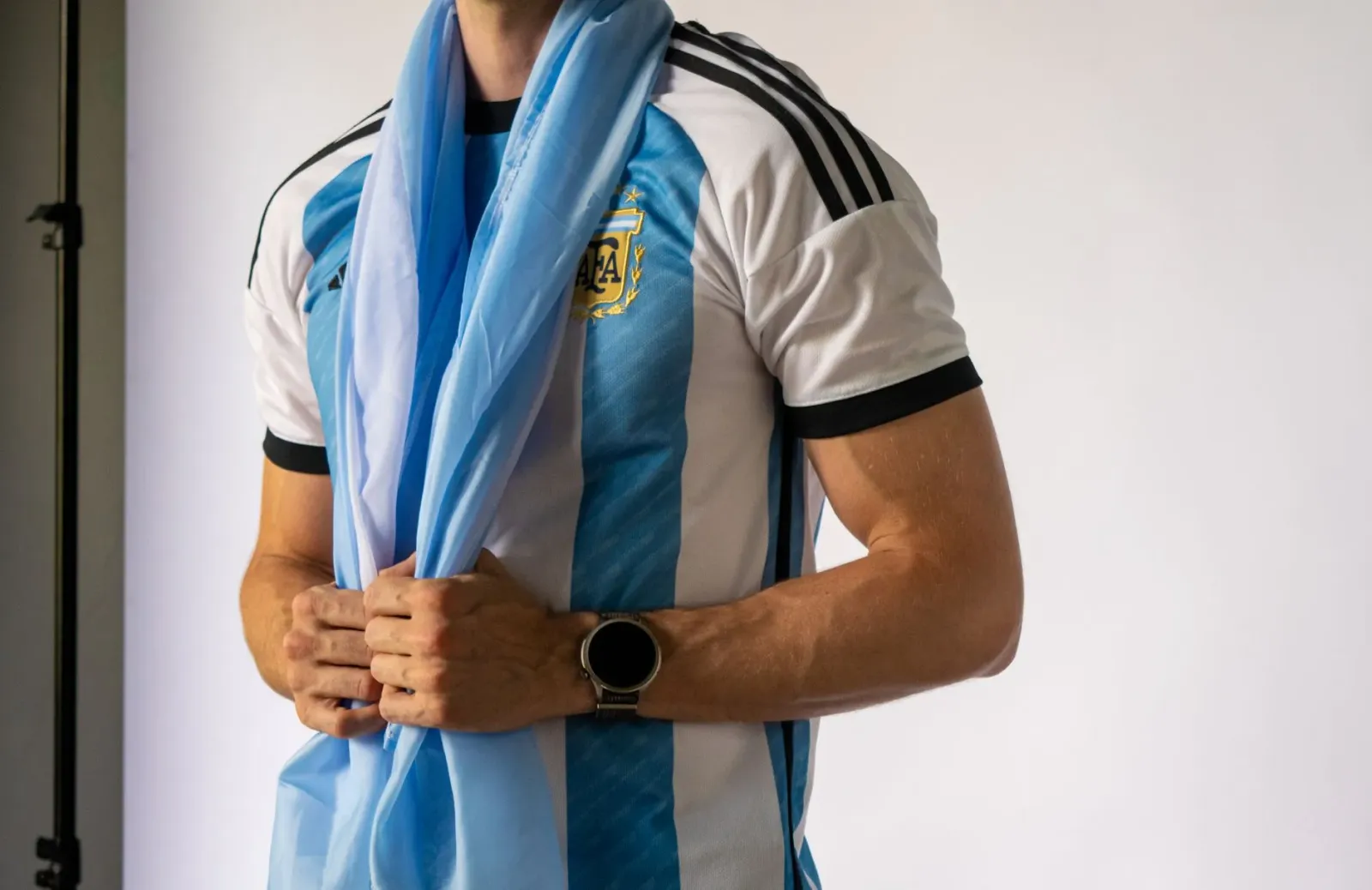 Ema jogadór Argentina nian halimar ho forsa no reziliénsia iha kampu futebol, iha fundu bandeira Argentina no torcedor sira