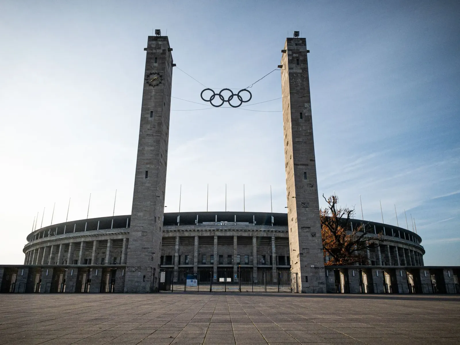 Imajen husi edifísiu sede IOC iha Lausanne, Suísa, ho bandeira olímpika no elementu desportu nian.