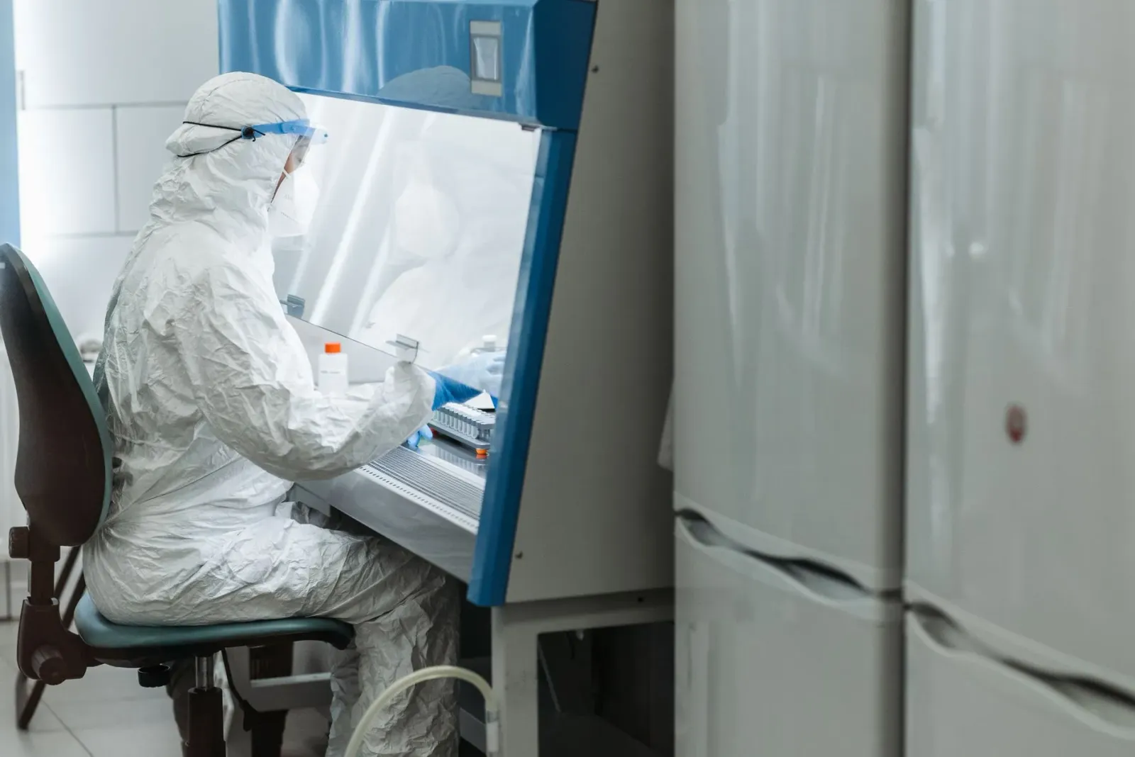 Imajen hosi edifísiu laboratóriu NIH iha Montana ho sinal seguransa no sientista uza roupa protesaun. Hanesan fatin ne'ebé si