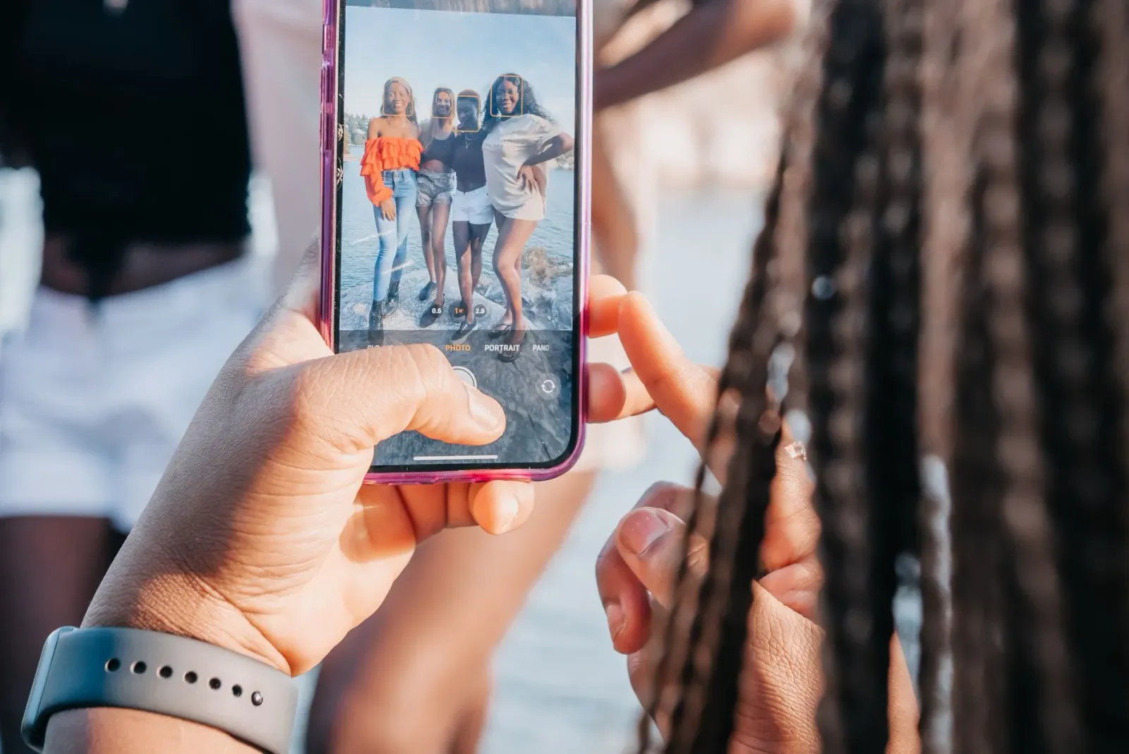 Ema feto ida uza smartphone atu fotografia nia an, ho teknolojia Universal Tone ne'ebé kaptura ton kulit auténtiku, iha fundo