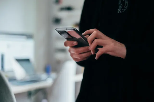 Ema ida kaer smartphone iha liman, ho expresão hanoin kona-ba sentidu moris, iha ambiente natural ho fokus ba ekilibriu entre