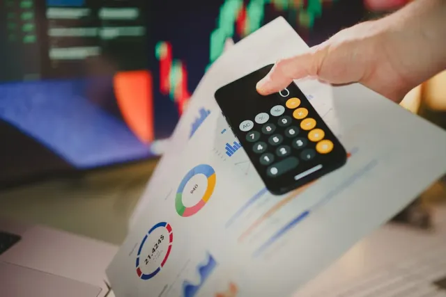 Imajen hatudu dokumentu finansa, kontabilidade, no konsellu impostu iha meja, ho laptop no kaneta, simboliza planeamentu fina