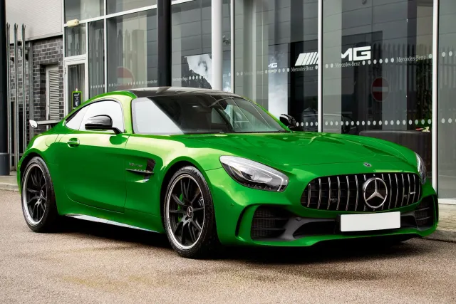 Karreta elétriku Mercedes-AMG GT 4-pórta coupe iha kór prata ho luz neon iha fundu eskuru, hatudu desen modernu no lais