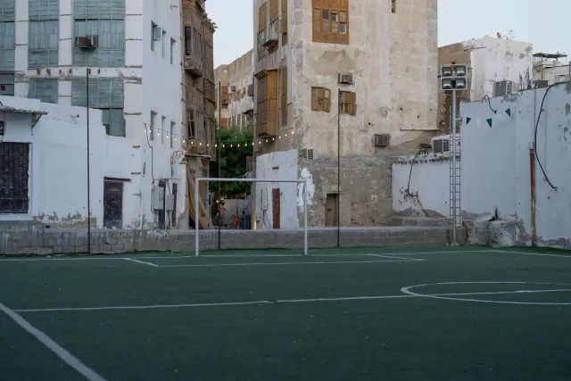 Imajen ida husi futebol iha kampu verde ho osan no bandeira Arabia Saudita iha kotuk, hanesan simbolu ba investimentu boot ih