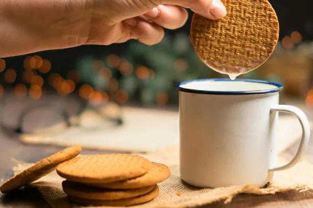 Ema ida dunka biskuat Gingernut iha xá mutin iha kopu vidru, ho liman kaer biskuat ne'ebé iha sorin, iha meja ai