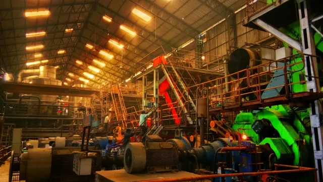 Fábrika manufatura iha India ho makina industrial no funsionáriu servisu hela, simboliza kresimentu produsaun industrial ne'e