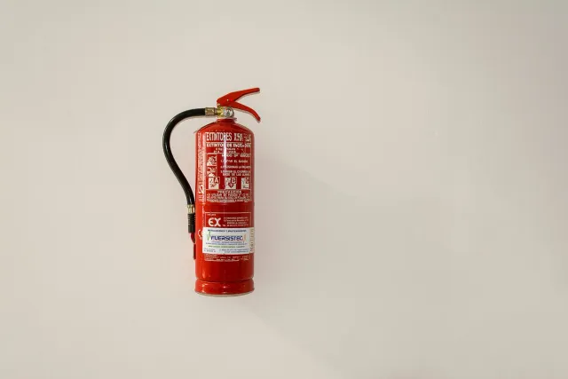 Imajen ida hatudu fábrika ho equipamentu seguransa no traballadór sira ho máscara respirasaun, iluminasaun neon, no sinalizas