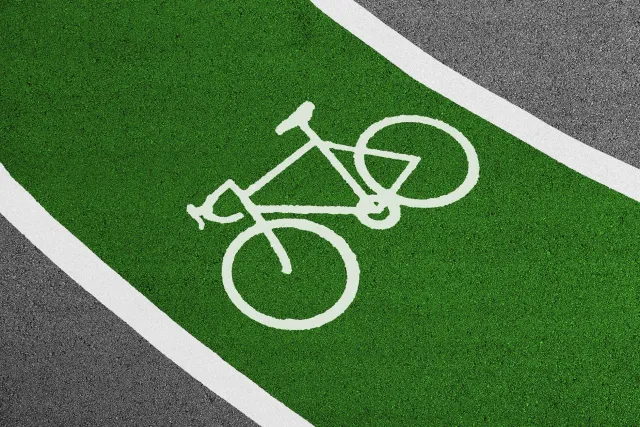 Imajen ida hatudu bike lane ne'ebé luan ki'ik liu fali símbolu siklu nian iha estrada urbana, ho siklista ida tenta uza lane 