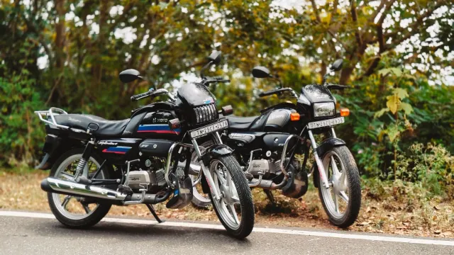 Imajen hatudu moto boot Hero MotoCorp iha área rurál Índia, ho ema sira tuur iha moto, hanesan sinal kresimentu venda moto bo