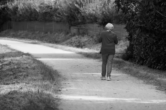 Ema idade médiu halo caminhada iha natureza, ho rosto sorrisu, hatudu oinsá movimentu isin ajuda atu atrasa idade no mantein 