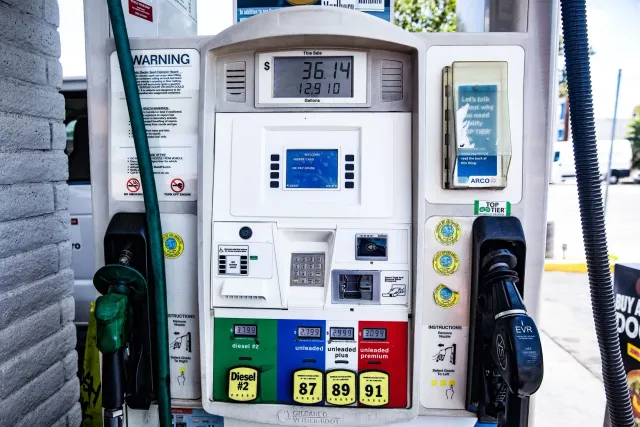 Ema ida iha estasaun gasolina haree prezu gasolina iha painél boot, ho bandeira Amerika iha kotuk, hatudu prezu ne'ebé monu.