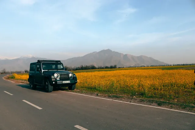 Família husi Timor-Leste viajen iha estrada ho karreta Mahindra, ho paisajem foho iha kotuk