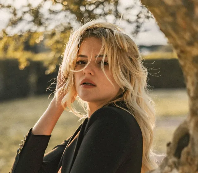 Imajen ida hatudu Mollie King sorri maibe ho expressaun kanek, hanesan ilustrasaun ba kolapsu súbitu ne'ebé nia esperiénsia t