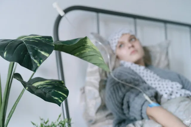 Pasiente kanser paru iha kama ospital ho esprasaun esperansa, iha janela ho luz naturale, hatudu forsa no reziliénsia durante