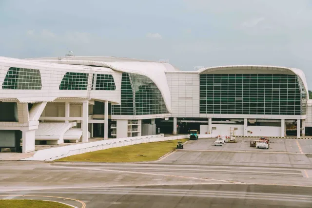 Imajen husi edifísiu terminal aeroportu Noida Internacional ne'ebé modernu, ho aviaun iha pista no konstruksaun kontinua.