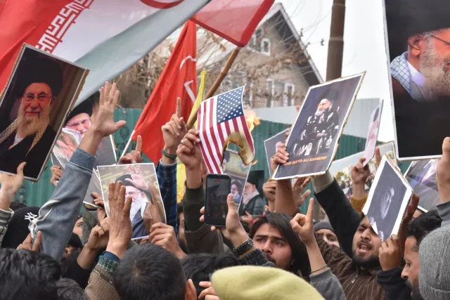 Imajen ida ne’e hatudu enkontru diplomátiku entre reprezentante Iran no Estados Unidos iha sala konferénsia, ho bandeira sira