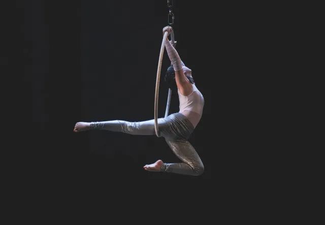 Ema sira iha plateia haree hela espetáculu Cirque du Soleil iha Disney World, ho luz sira ne'ebé brilhante no artista sirkus 