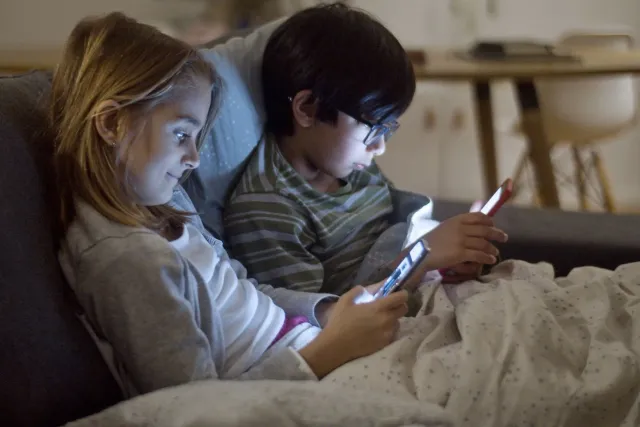 Labarik kiak sira uza telemóvel no tablet iha sala ida, ho espesialista ida iha kotuk fó avizu kona-ba krísis uzu ekrã. Imaje