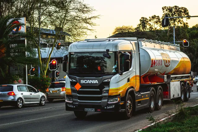 Kamiaun elétriku Scania nian iha estasaun karregamentu, ho kor azul no prateadu, iha ambiente urbano