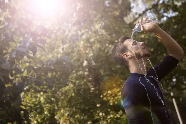 Imajen ida ne'ebé hatudu ema ida hemu bee iha tempu manas, ho sombra iha kotuk, atu prevene heatstroke.