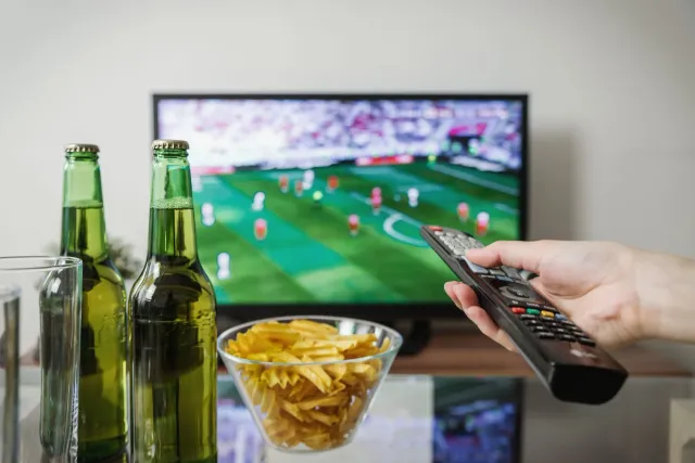 Ema haree partida fuból iha TV MiniLED 65-inch iha sala família, ho ekrã klaru no kór vibrante, hatudu teknolojia MiniLED nia