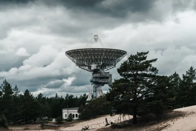 Imajen hatudu infraestrutura AI: data center ho komputador barak, radar previsaun clima, no ema uza ChatGPT iha laptop atu so