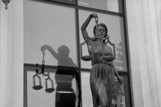 Imajen ida ne'ebé hatudu labarik sira tuur iha tribunal, ho juiz ida koalia, hanesan simbolu justisa ba labarik sira kontra l