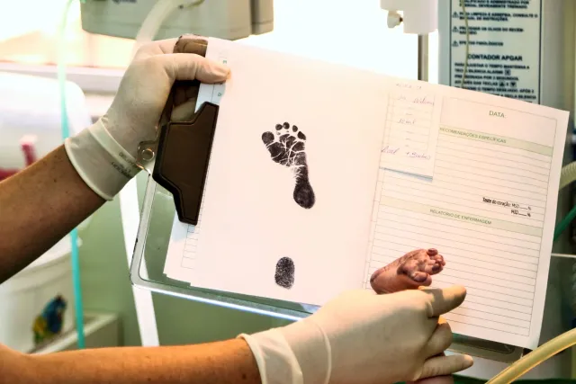 Imajen ida hatudu bebe foin moris iha hospital, ho enfermeira ida fó kuidadu neonatal, simboliza prevensaun mortalidade labar