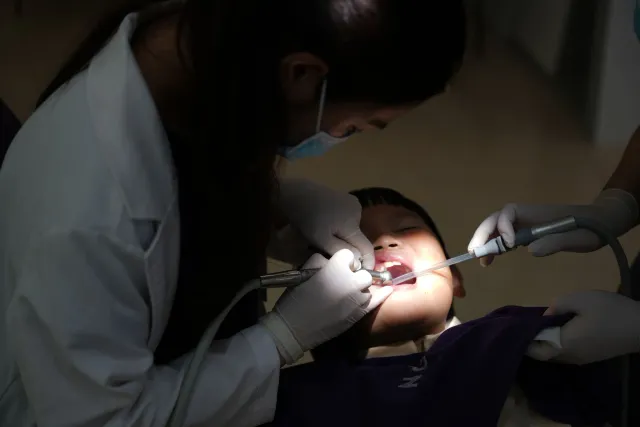Imajen ida hatudu labarik ki'ik ho nén bebé no vaksina, simboliza saúde global no kuidadu oral iha 2025