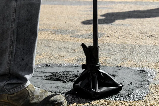 Imajen ida hatudu dalen estrada asfaltu ho pothole boot, iha laran iha sensór no drone ki'ik ne'ebé monitoriza, ho teknolojia