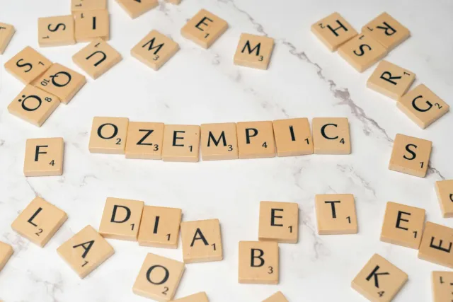 Imajen hatudu pen injesaun Ozempik iha mesa, ho fundu botika no fatin vaksinasaun, hanesan ilustrasaun kona-ba remediu obezid