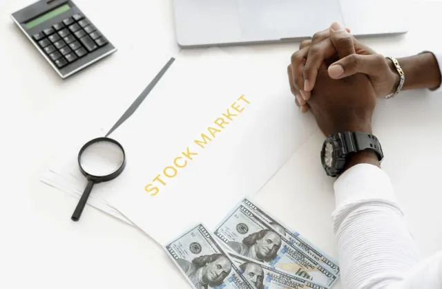 Ema sira tuur hamutuk iha meja ida, diskute kona-ba fundu sosiál finansa no impaktu investimentu, ho dokumentu no laptop iha 