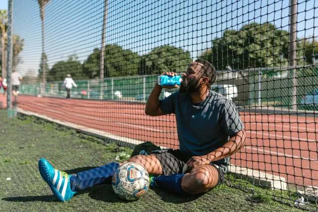 Jogadór futebol iha World Cup 2026 hemu bee durante hydration break iha jogu, ho treinadór no árbitru iha kotuk.