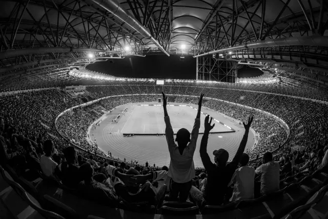 Atleta feto halai no hatudu emosaun alegria iha estadiu ho torcedór barak iha fundu, hanesan espresaun rai emosaun iha despor