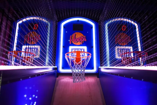 Ema na'in rua tuir hela programa morning TV iha sala ida, ho televizaun boot hatudu jogu NBA Finals iha laran. Iha sofá moder