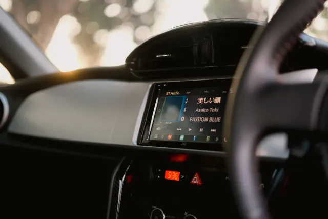 Imajen husi tela sentru karreta ne'ebé hatudu jogu Android Auto hanesan Asphalt 9, ho volante no painél instrumentu iha fundu