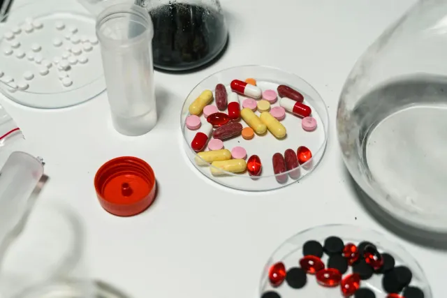 Suplementu NAD+ iha laboratóriu peskiza sientífika, ho tablete no frasku iha meja laboratóriu