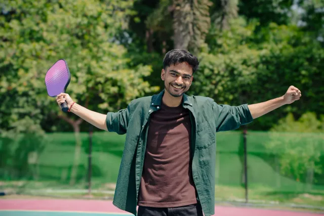 Labarik feto treinu pickleball iha dader-dukur ho raquete no bola iha kampu, hatudu disiplina no konsentrasaun