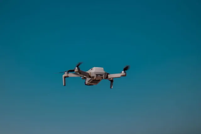 Imajen ida ne'ebé hatudu drone submarinu AUKUS iha tasi laran, ho luz azul no infraestrutura kabu submarinu, hodi ilustra tek