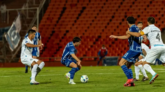 Jogador futebol modernu ho korpu forte no múskulu, halai iha kampu verde ho intensidade aas, hatudu mudansa husi futebol anti