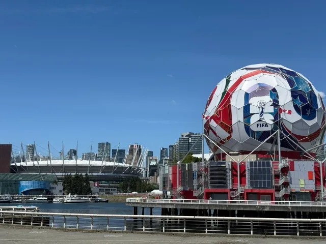 Imajen ne'ebé hatudu jogador futebol iha rai manas boot ho sinal temperatura aas iha stadium durante FIFA World Cup 2026, hat